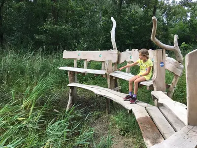 a young child sitting on a wooden bench at Vakantiewoning Pelterheggen in Grote Heide