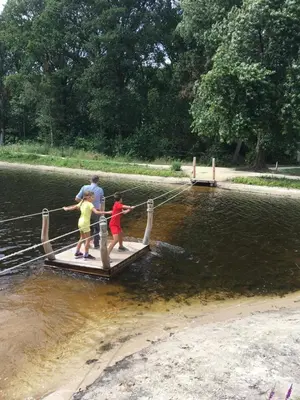 a man and two children on a dock in the water at Vakantiewoning Pelterheggen in Grote Heide