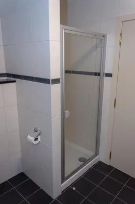 a shower with a glass door in a bathroom at Vakantiewoning Pelterheggen in Grote Heide