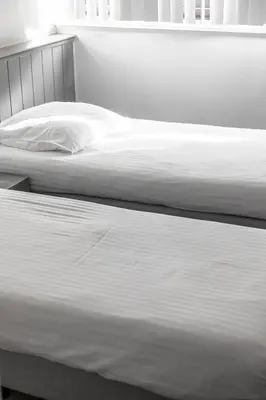 two beds in a bedroom with white sheets at Esplanada Studios in Genk