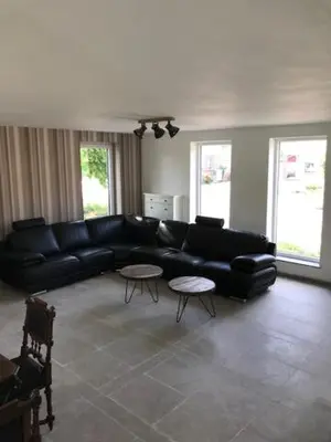 a living room with a black couch and two tables at Bij de lindeboom in Maaseik
