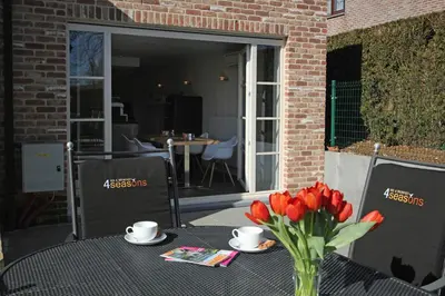 a table with a vase of red tulips on a patio at B&B 4 Seasons in Riemst