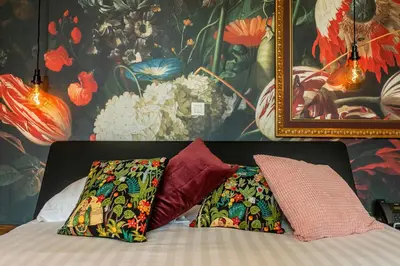 a bed with two pillows on it with a painting at BareFoodGIULIA - Inspiration Hotel in Hasselt
