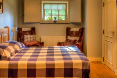 a bedroom with a bed and two chairs and a window at Vakantiehuis Aen de Roderburgh in Maaseik