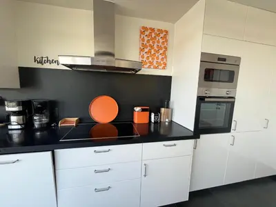 a kitchen with white cabinets and an orange plate on the counter at GT Lounge in Heusden - Zolder