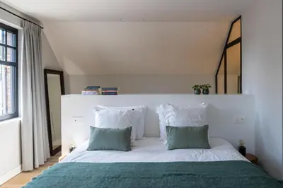 a bedroom with a white bed with green and white pillows at De Sjieper in Lanaken