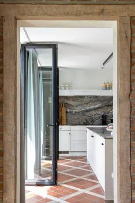 a kitchen with white cabinets and a glass door at De Sjieper in Lanaken
