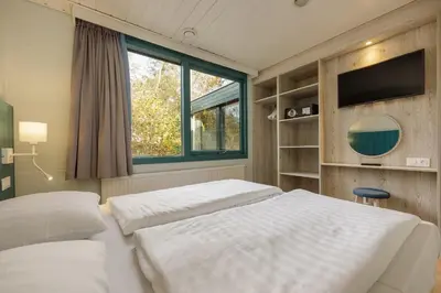 a bedroom with two beds and a tv and a window at Center Parcs Erperheide in Peer