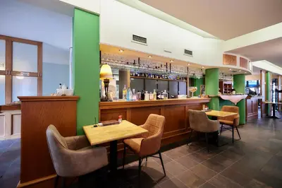 a restaurant with two tables and a green wall at Hotel Ambiotel in Tongeren