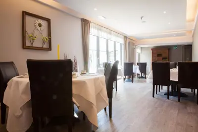 a dining room with tables and chairs and a window at Hotel Ambiotel in Tongeren
