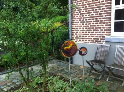 a garden with two pieces of art next to a bench at De Oude Molen in As