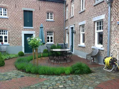 a patio with a table and chairs in front of a brick building at De Oude Molen in As