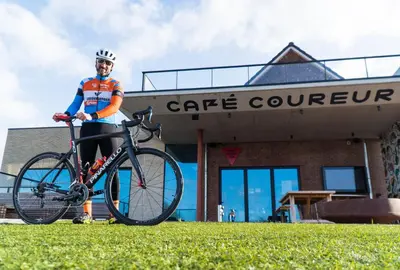a man standing next to a bike in front of a building at Café Coureur Borgloon in Borgloon