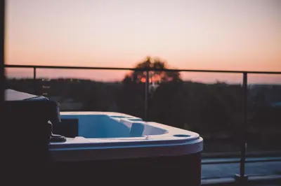 a hot tub on a balcony with a sunset in the background at Café Coureur Borgloon in Borgloon