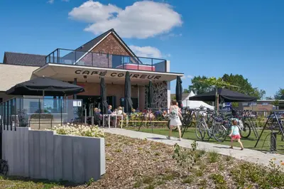 a group of people walking down a sidewalk in front of a cafe at Café Coureur Borgloon in Borgloon