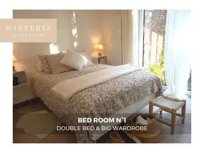 a bedroom with a bed with a bed roommit double bed and big window at Wisteria Guest House in Villers-lʼÉvêque