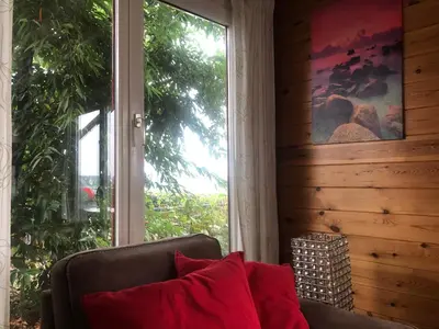 a couch in a room with a large window at Thuiskomen, genieten aan het water in Maaseik