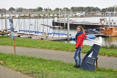 a woman is standing next to a sign near a marina at Thuiskomen, genieten aan het water in Maaseik