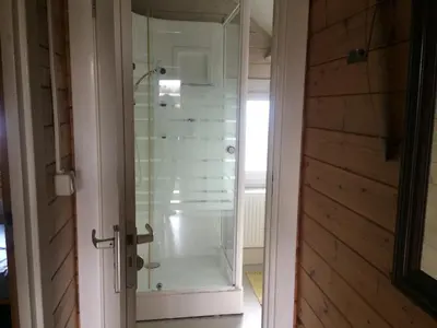 a glass shower in a room with a door at Thuiskomen, genieten aan het water in Maaseik