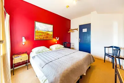 a bedroom with a red wall with a bed at De Appelgaard in Sint-Martens-Voeren