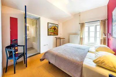 a bedroom with a bed and a bathroom with a shower at De Appelgaard in Sint-Martens-Voeren