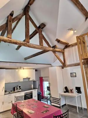 a kitchen with a table and some wooden ceilings at Gîte Cour Delhez in Olne