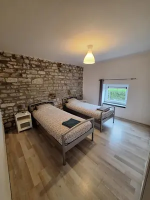 a room with two beds and a brick wall at Gîte Cour Delhez in Olne