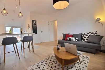a living room with a couch and a laptop on a table at Gats Place in Liège