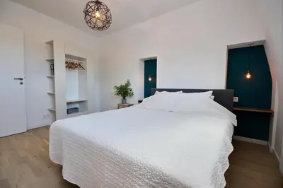 a bedroom with a large white bed and a chandelier at Gats Place in Liège