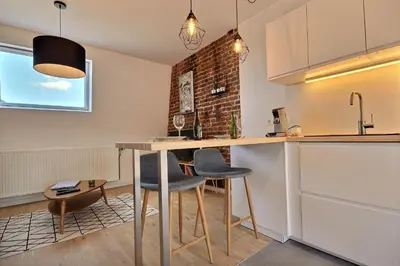 a kitchen with a table and chairs and a brick wall at Gats Place in Liège