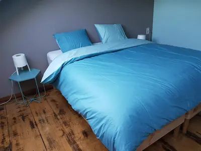 a bed with a blue comforter and a side table at Espace Douffet - Un havre de paix en pleine ville in Liège