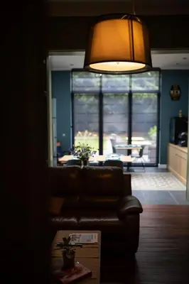 a living room with a leather couch and a lamp at B&B Gaudium XII in Tongeren