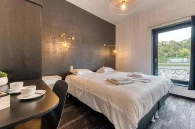 a bedroom with a bed and a table and a window at Hôtel Mosa in Hermalle-sous-Argenteau