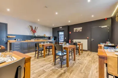 a restaurant with tables and chairs and a kitchen at Hôtel Mosa in Hermalle-sous-Argenteau