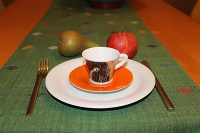 a cup of coffee on a plate next to an apple at Beau Reg'Art in Hasselt