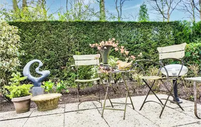 a garden with two chairs and a statue and plants at Beautiful Home In Rekem-Lanaken in Bovenwezet