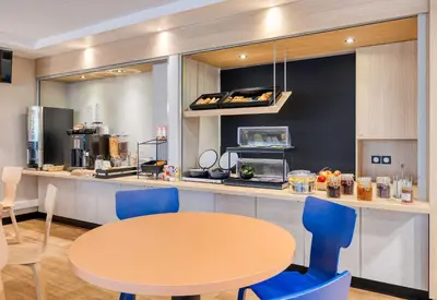 a kitchen with a table and blue chairs and a counter at B&B HOTEL Liège Rocourt in Liège