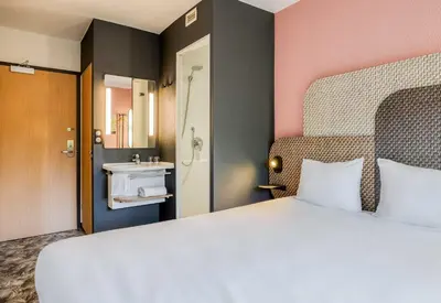 a bedroom with a large bed and a bathroom at B&B HOTEL Liège Rocourt in Liège