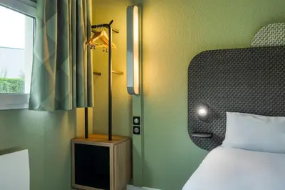 a bedroom with a bed and a lamp next to a window at B&B HOTEL Liège Rocourt in Liège