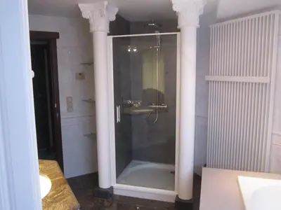 a bathroom with a shower with two white columns at Vakantiewoning Upstairzzz in Kortessem