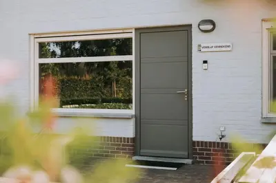 a gray door on a house with a window at Vakantiewoning Vennekens in Peer