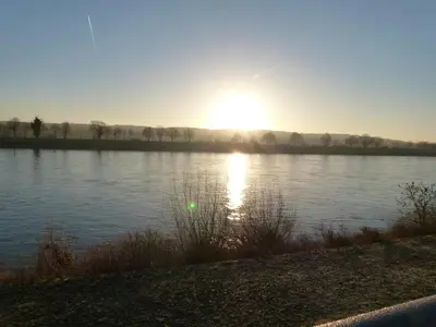 a sunset over a lake with the sun reflecting on the water at De Konik in Uikhoven
