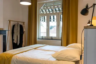 a bedroom with a bed in front of a window at VillaEnzo - ELEGANT HERENHUIS - 14P - 6SLPK - SAUNA - INFRAR CABINE - OFYR BBQ - 15MIN Maastricht in Zussen