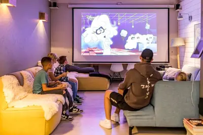 a group of people sitting in a room watching a presentation at ZussEnzo - STOER FAMILIEHUIS - 18P - 5SLPK - GROTE TUIN - SAUNA - OFYR BBQ - HOMECINEMA - 15MIN MAASTRICHT in Zussen