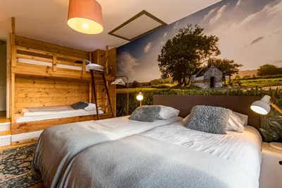 two beds in a room with a mural on the wall at ZussEnzo - STOER FAMILIEHUIS - 18P - 5SLPK - GROTE TUIN - SAUNA - OFYR BBQ - HOMECINEMA - 15MIN MAASTRICHT in Zussen