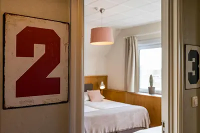 a bedroom with a bed and a window and a red sign at ZussEnzo - STOER FAMILIEHUIS - 18P - 5SLPK - GROTE TUIN - SAUNA - OFYR BBQ - HOMECINEMA - 15MIN MAASTRICHT in Zussen