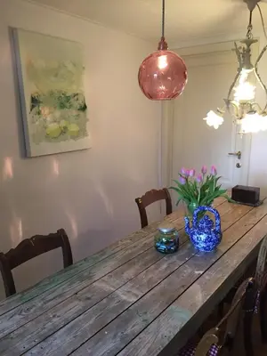 a wooden table with a blue vase and flowers on it at PuurTeuven B&B tussen Kunst en Natuur in Voeren