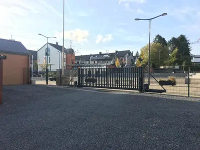 a gate in a parking lot with houses and street lights at Hotel-Restaurant Zum Onkel Jonathan in Raeren