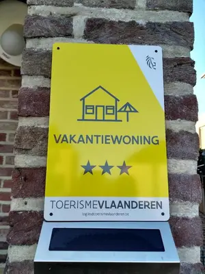 a yellow sign on a brick wall with a house at Hasbania Vakantiewoning in Gingelom