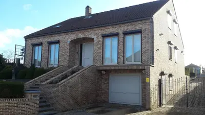 a brick house with two white garage doors at Hasbania Vakantiewoning in Gingelom